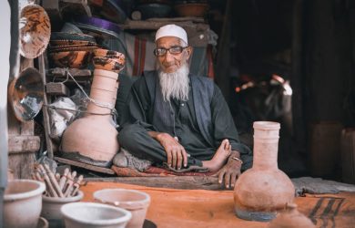 man in gray long sleeve shirt sitting beside brown clay pots