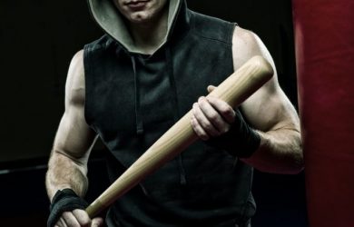 man in black and gray hoodie holding brown wooden stick