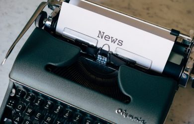 green and white typewriter on brown wooden table