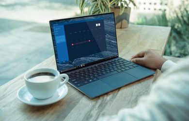 person using black laptop computer on brown wooden table