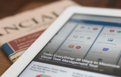 white tablet computer on top of newspaper