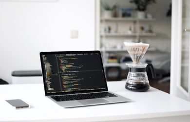 black laptop computer beside clear glass cup