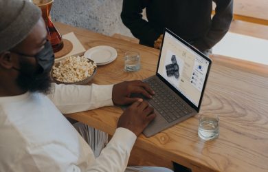Person sitting on a table on Surface laptop wearing a mask
