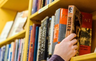 person holding book in book shelf