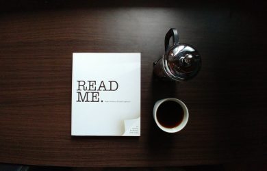 flat-lay photo of Read Me. book beside cup and silver mug on table