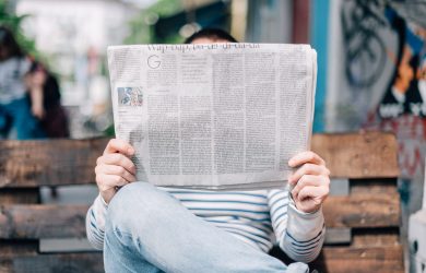 man sitting on bench reading newspaper