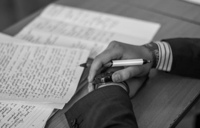 Grayscale Photography of Person Holding Pen