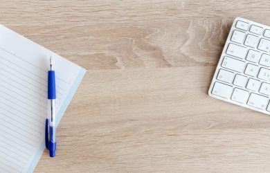 Blue Retractable Pen on Top of Notebook Near Magic Keyboard