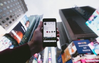 high angle photo of person holding turned on smartphone with tall buildings background